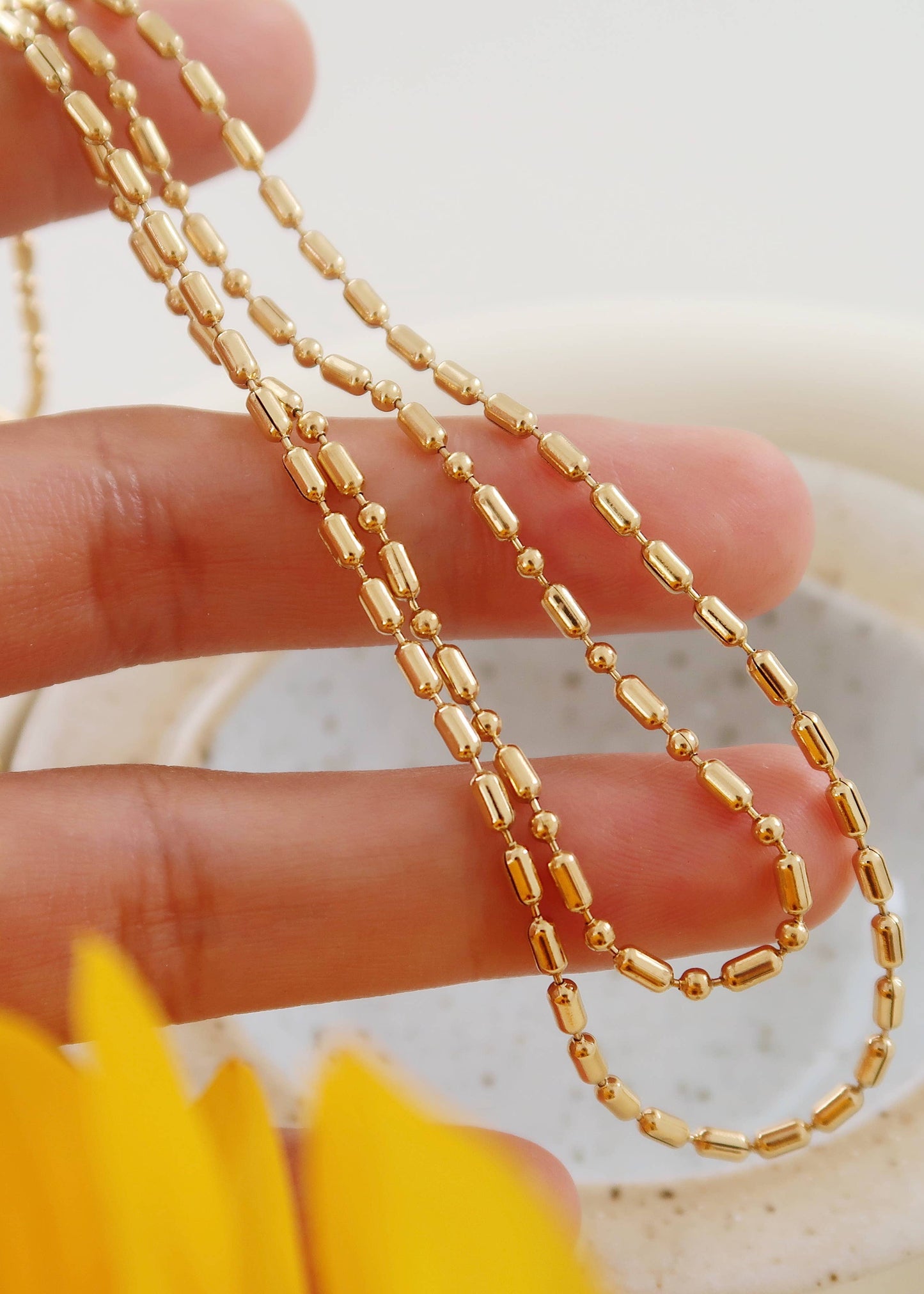 Gold chain held between fingers with a blurred background