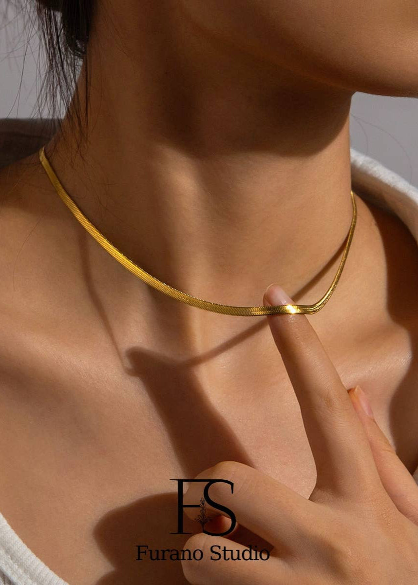 Gold necklace being worn and adjusted by a person, with 'Furano Studio' branding.
