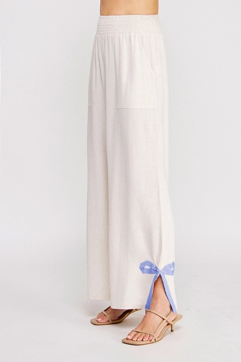 White wide-leg pants with a blue ribbon tie on a white background