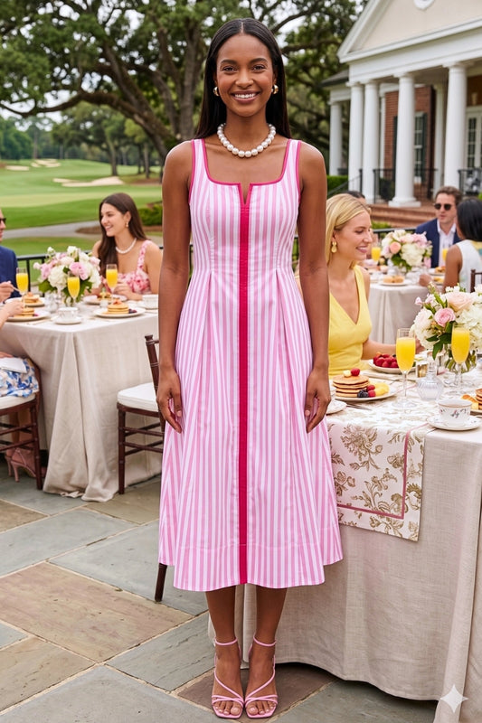 Woman in a pink and white dress standing outdoors at a formal event with tables and guests.