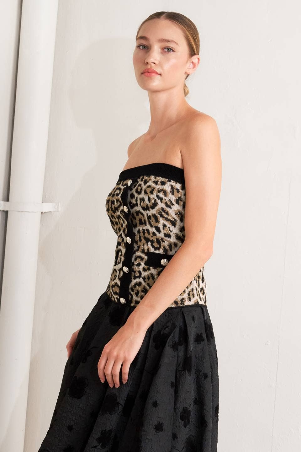 Woman wearing a leopard print top and black skirt against a white background