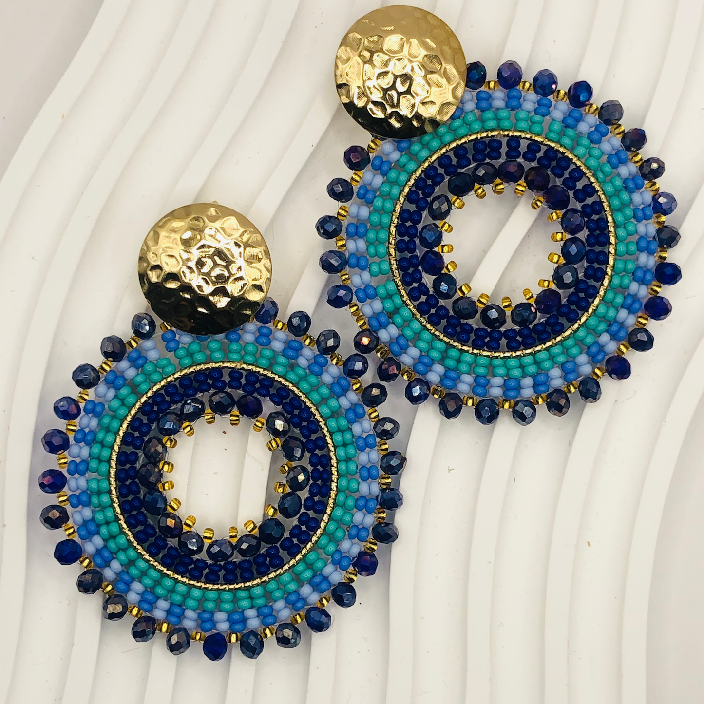 Pair of beaded earrings with blue and gold design on a white background