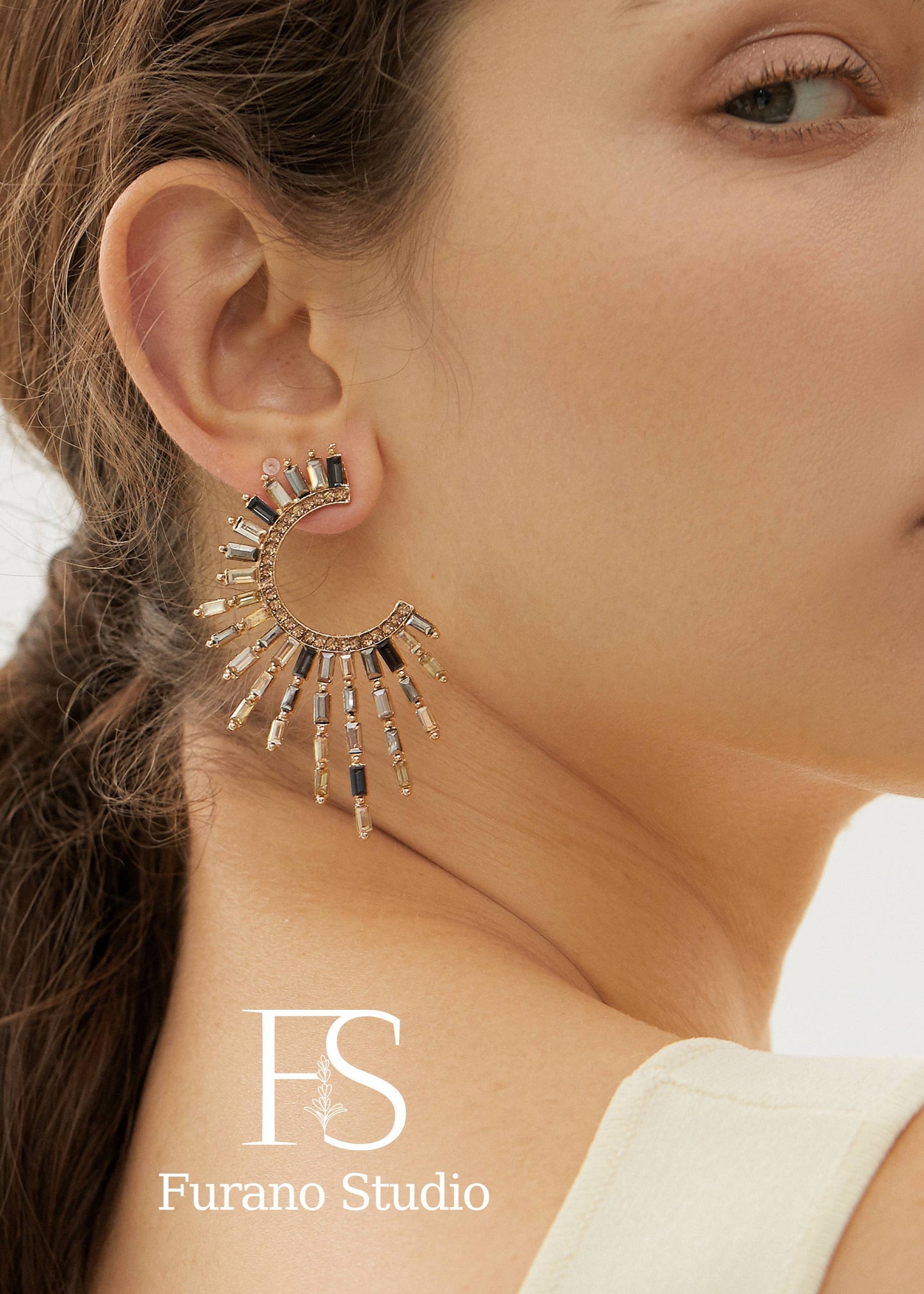Close-up of a woman wearing a gold earring with 'Furano Studio' branding.