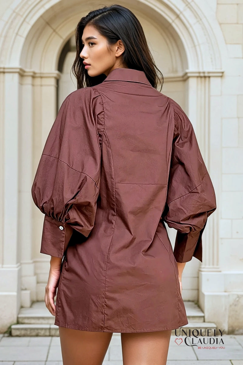 Woman wearing a brown jacket in front of a stone archway