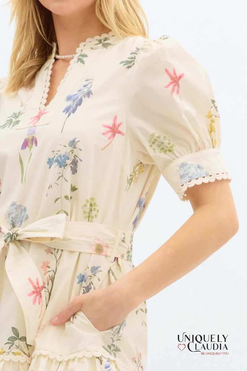 Woman wearing a floral dress with a plain background, featuring the brand 'Uniquely Claudia'.