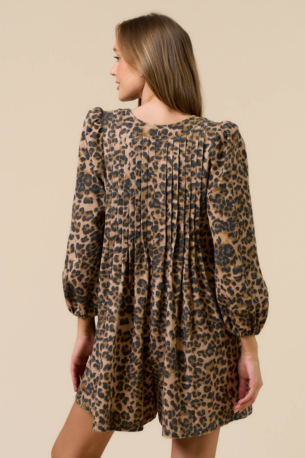 Woman wearing a leopard print romper against a beige background