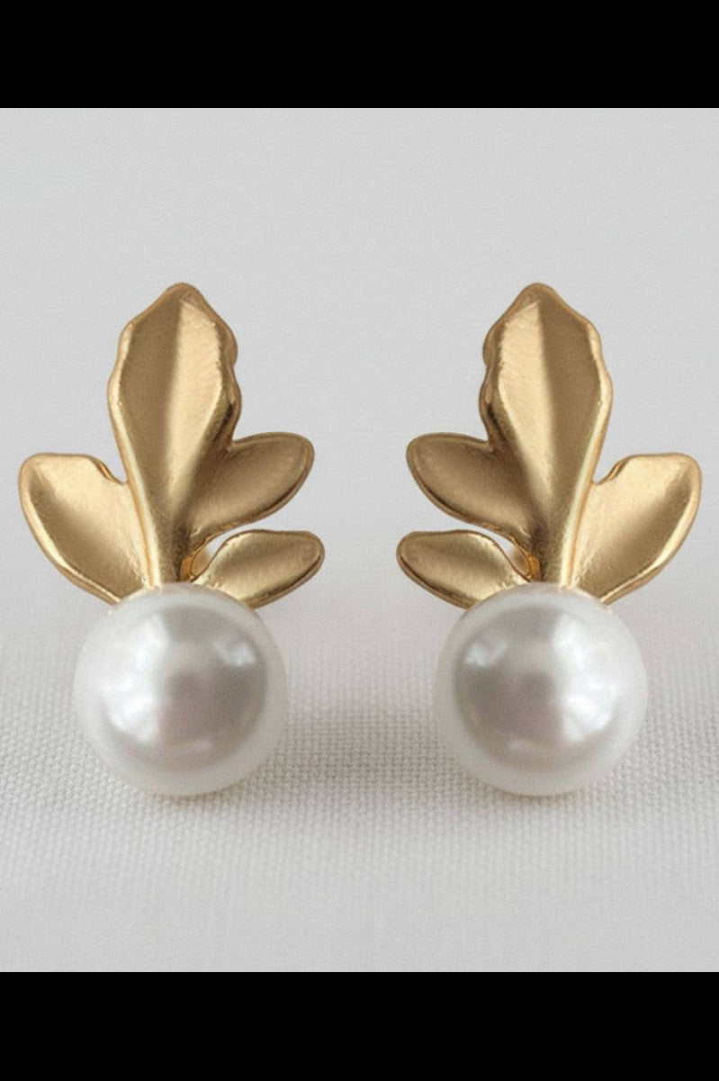 Gold leaf earrings with pearl centers on a light gray background