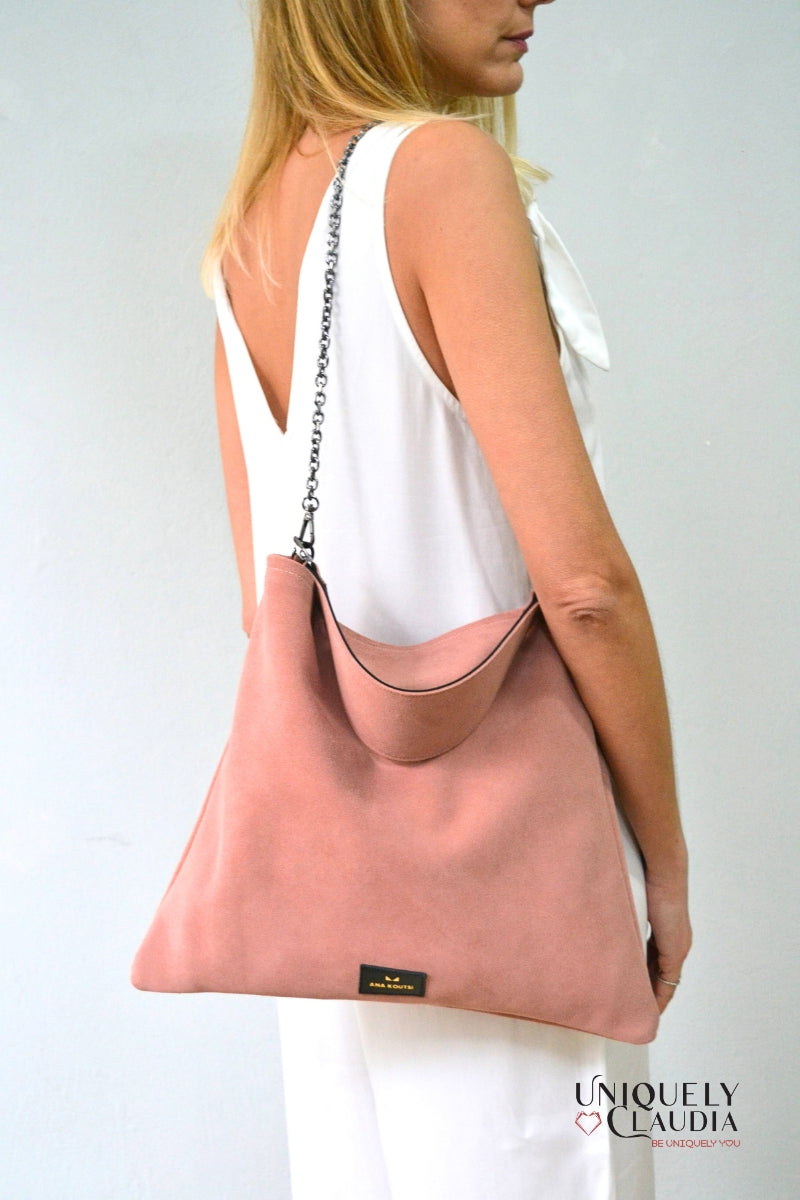 Woman carrying a pink handbag with 'Uniquely Claudia' branding on a plain background