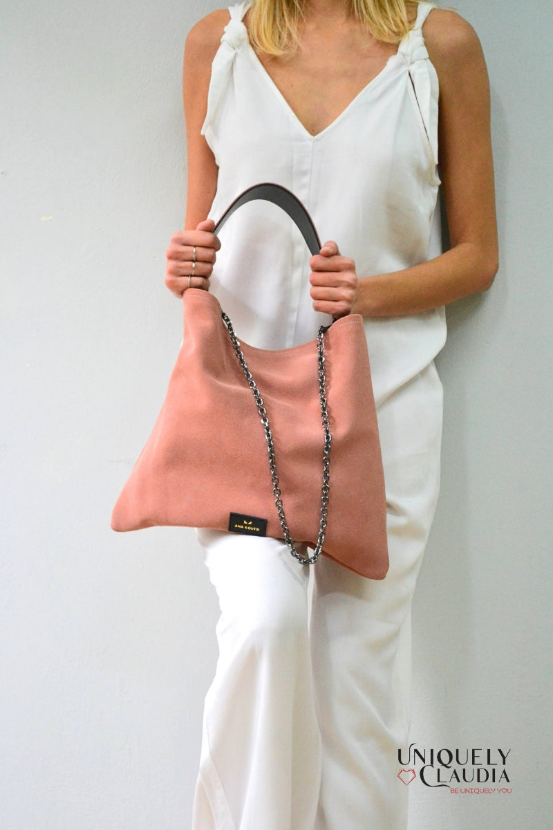 Woman holding a pink handbag with a white background, featuring the brand 'Uniquely Claudia'.