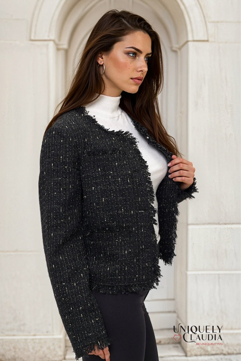 Woman wearing a black tweed jacket in front of a stone archway