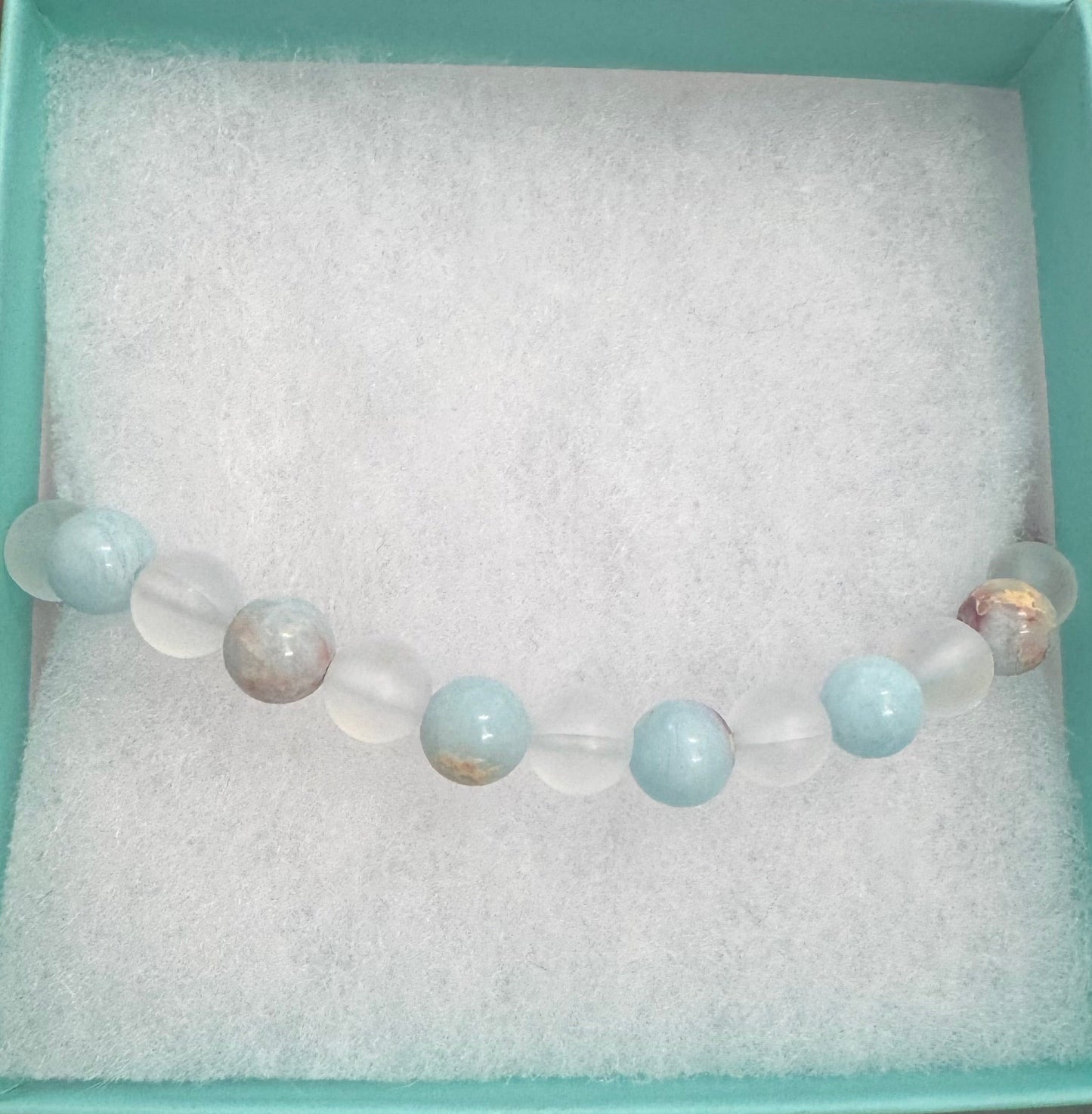 Bracelet with beads in a light blue box held by a person.