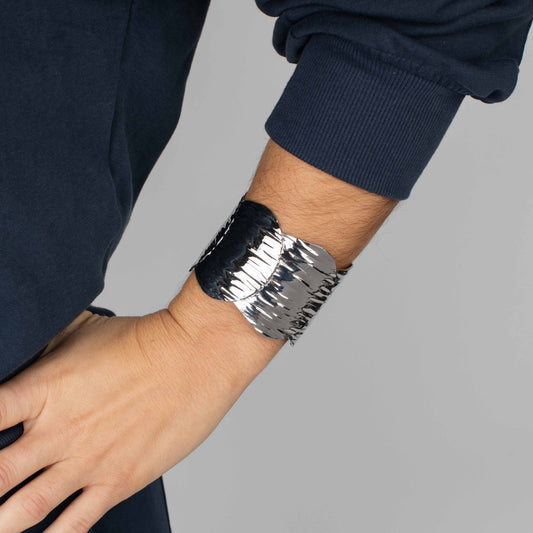 Silver bracelet on a wrist against a gray background