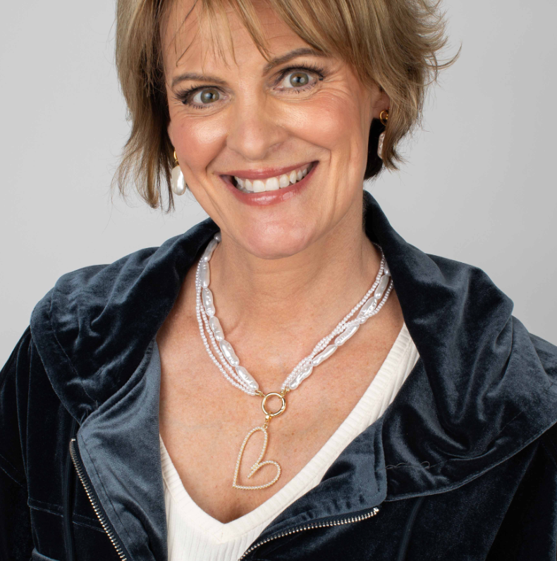 Woman wearing a necklace with a heart pendant against a gray background