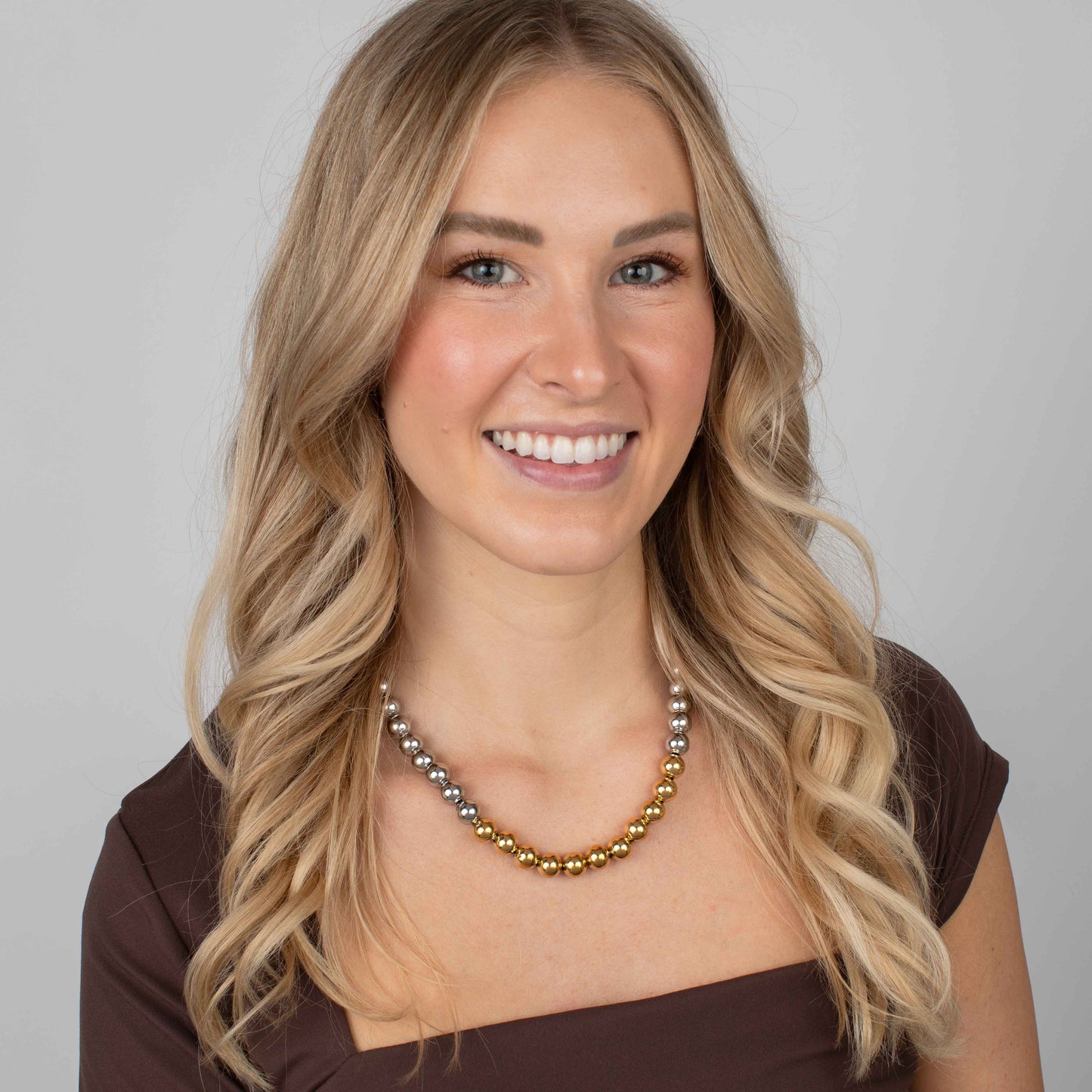 Woman wearing a beaded necklace with a plain background