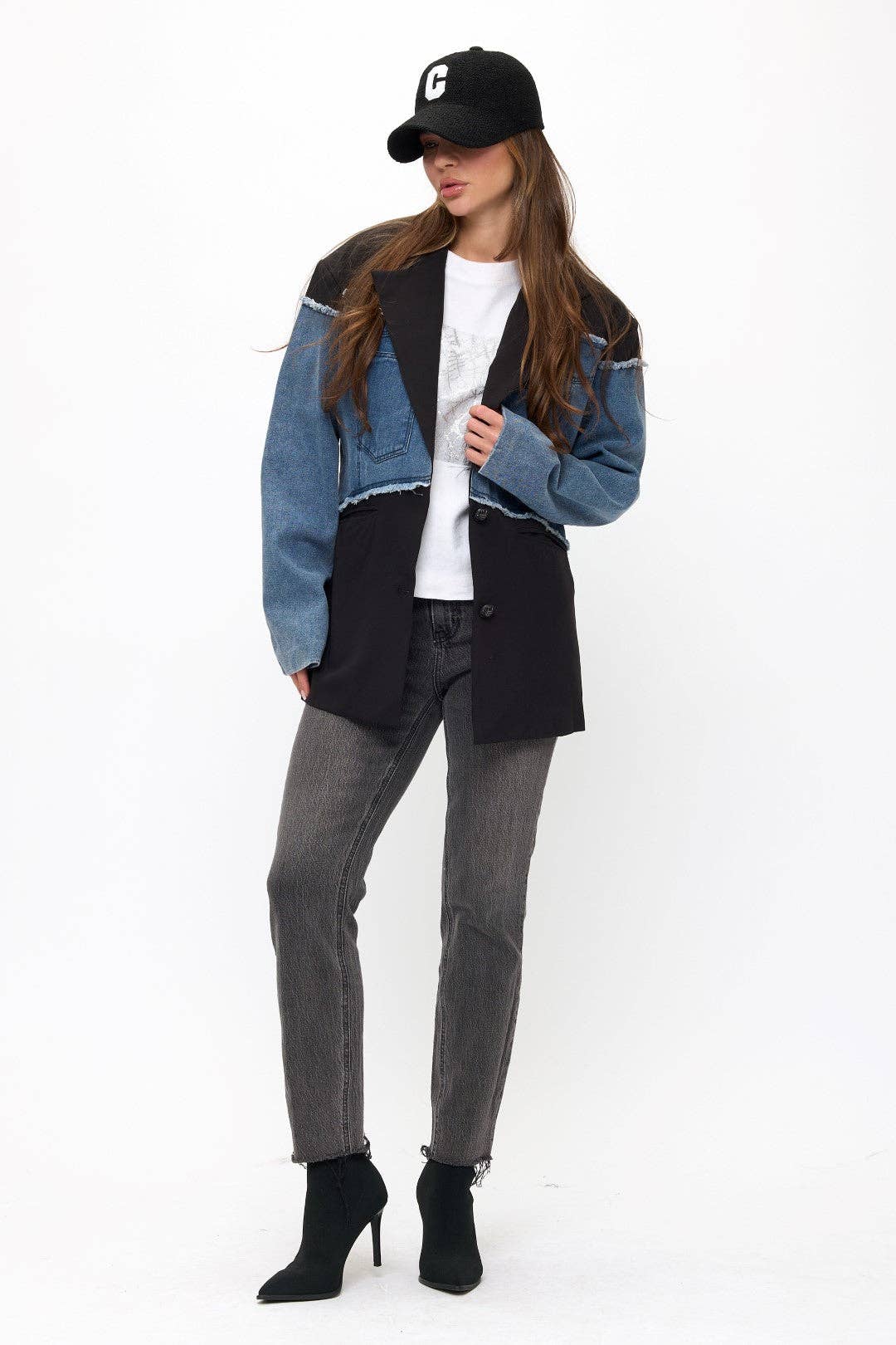Woman wearing a patchwork jacket, white shirt, gray pants, and black boots on a white background