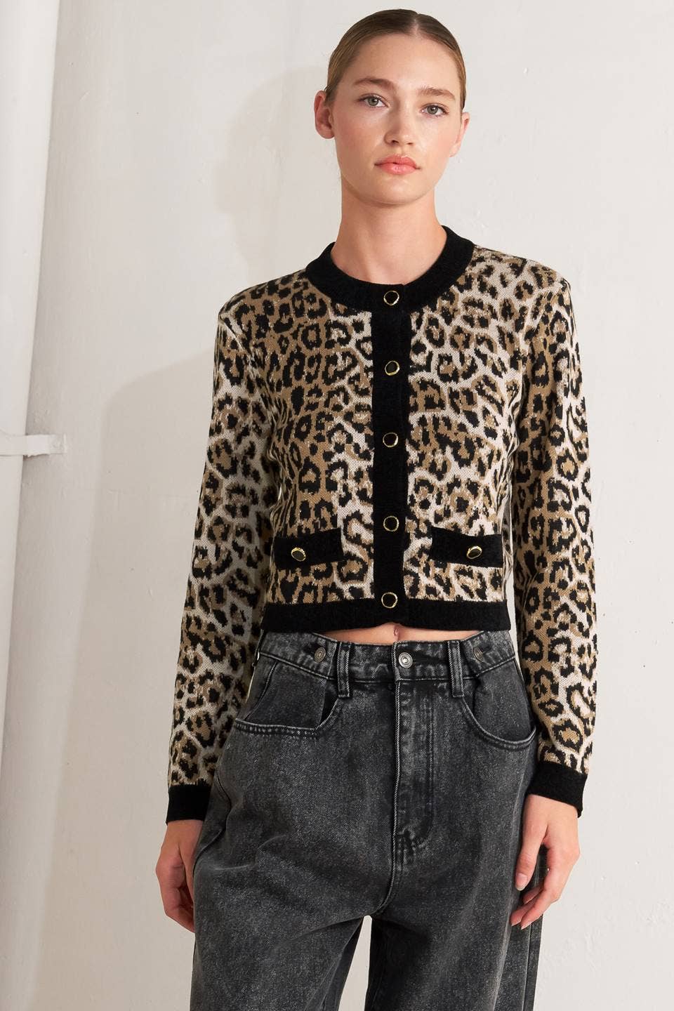 Model wearing a leopard print cardigan with black trim and high-waisted jeans against a white background