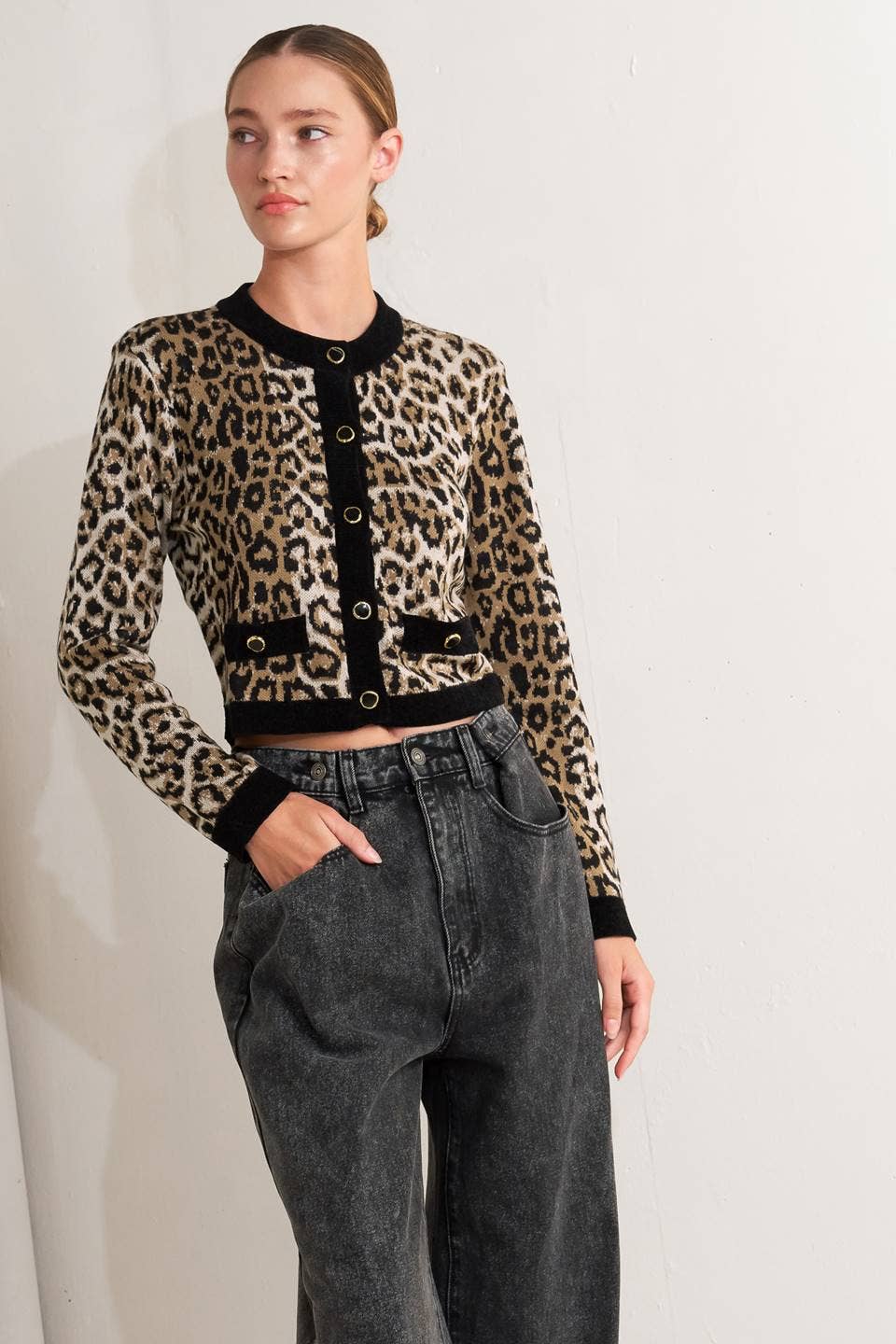 Woman wearing a leopard print cardigan with black trim on a white background