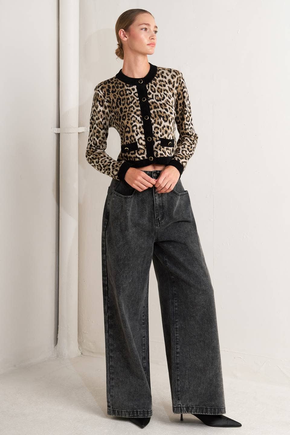 Person wearing a leopard print jacket and black jeans on a white background