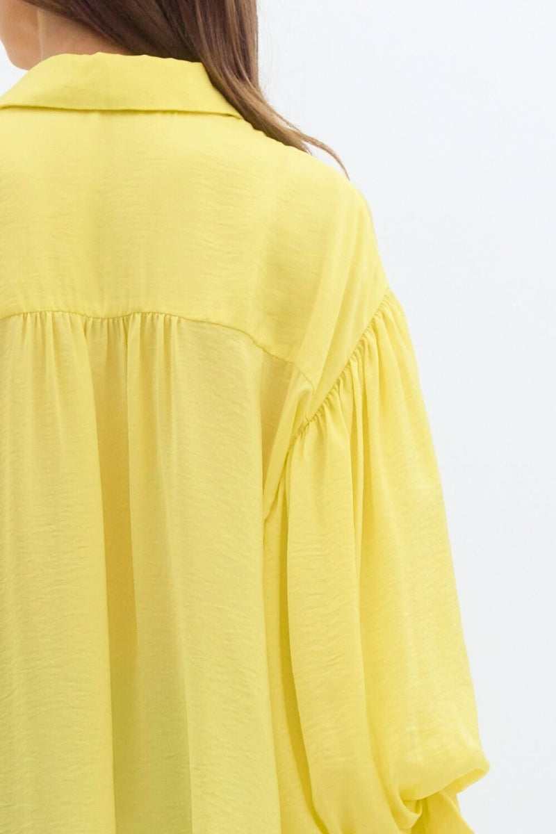 Yellow blouse worn by a person on a white background