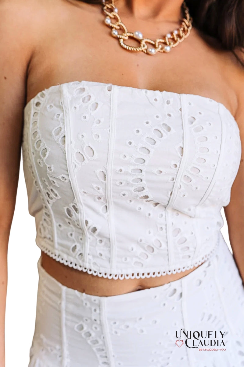 White strapless top with intricate cut-out design worn by a person, with 'Uniquely Claudia' branding.