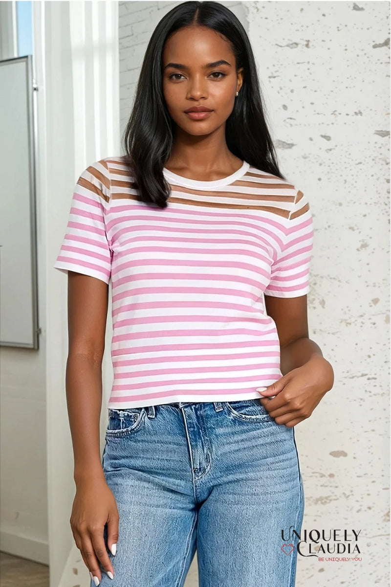 A woman wearing a white t-shirt with bold color block stripes in pink and black, paired with blue jeans.