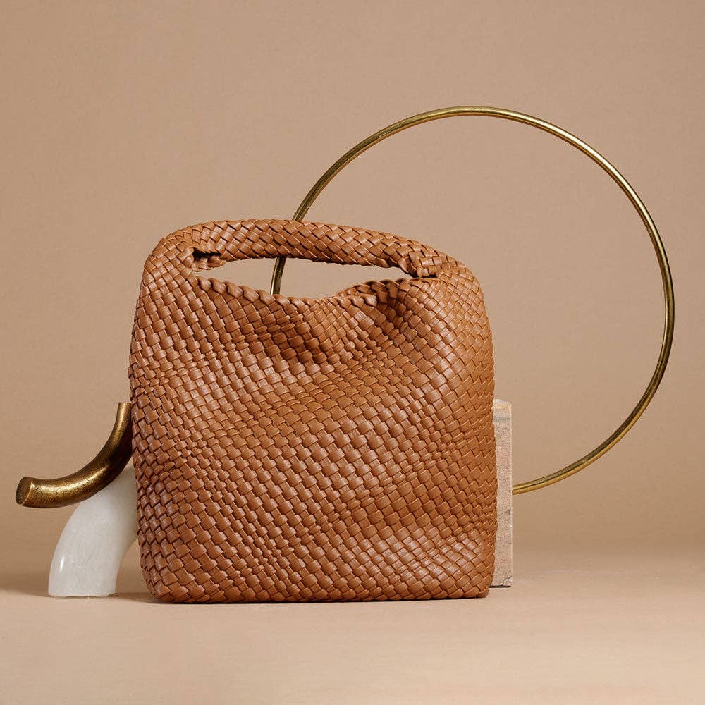 Woven saddle handbag with gold handle on a beige background