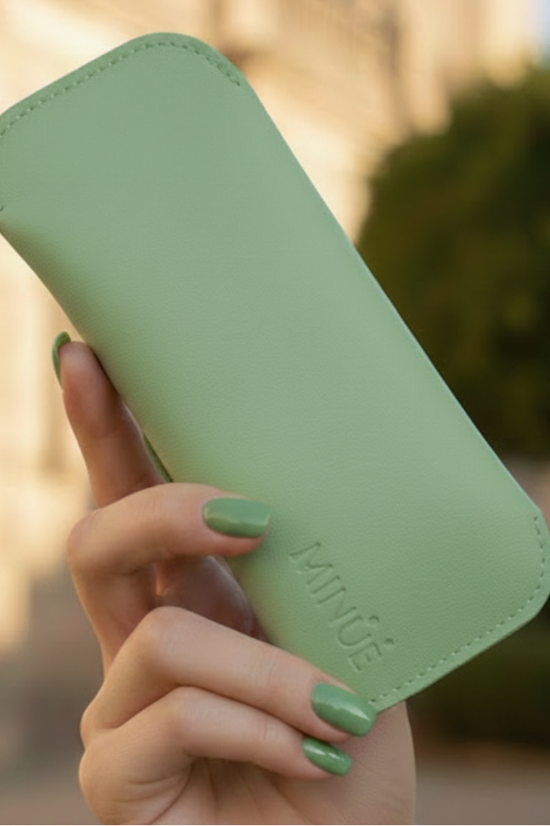 Hand holding a green phone case with 'ZIVY' branding outdoors.