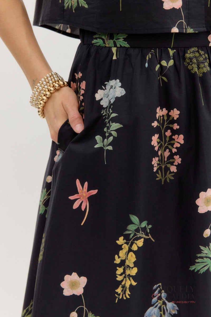Black dress with colorful floral pattern held by a person on a white background