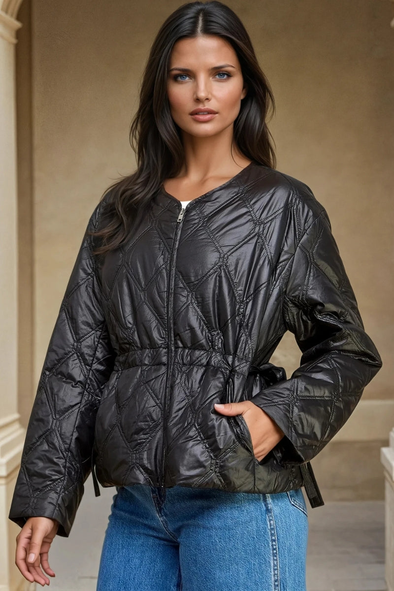 Woman wearing a black quilted jacket with a neutral background