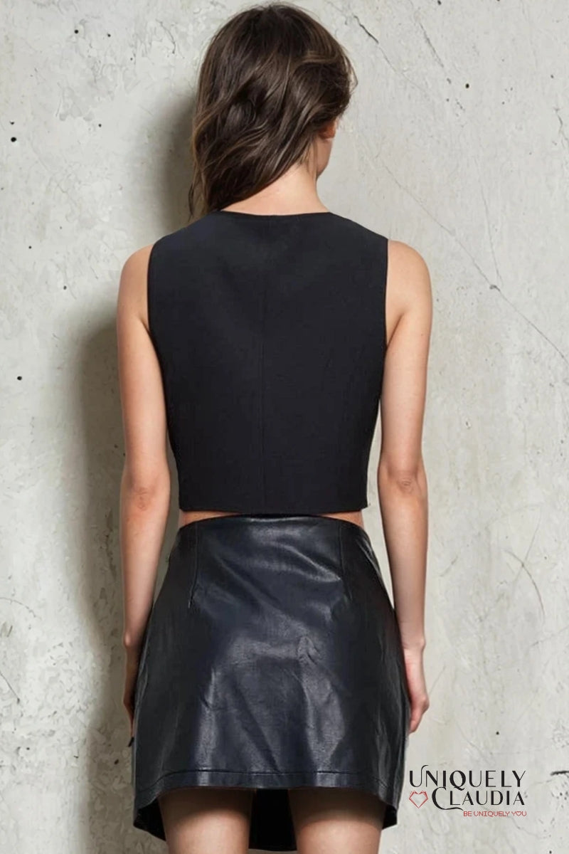 Woman wearing a black sleeveless top and leather skirt against a textured wall, with 'Uniquely Claudia' branding.