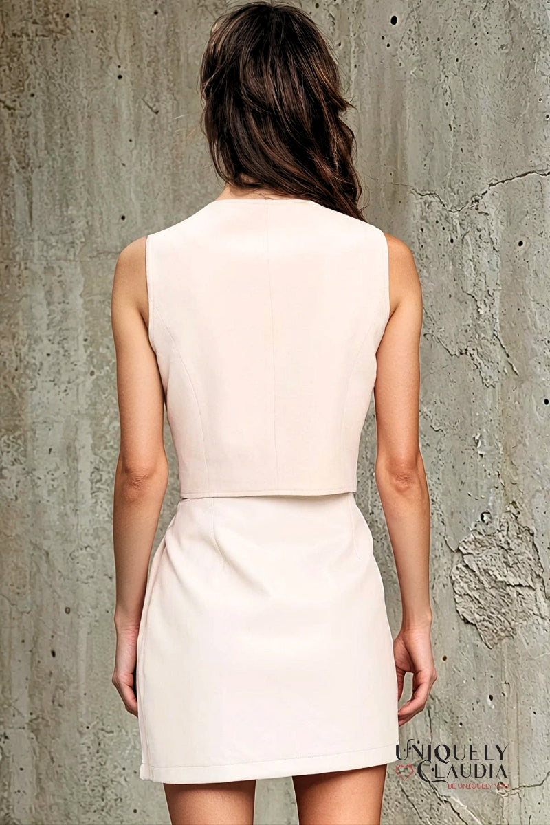 Woman wearing a white dress against a textured gray wall, with 'UNIQUELY CLAUDIA' branding.