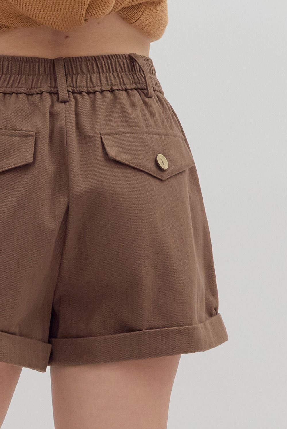 Brown shorts with a button on a plain background