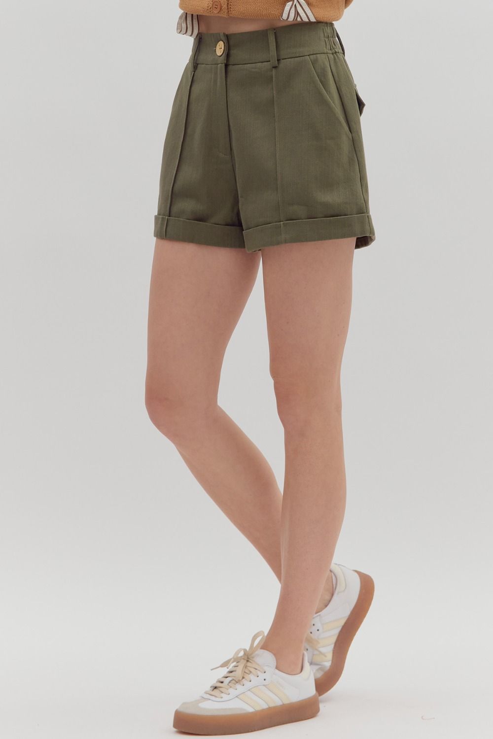 Person wearing olive green shorts on a plain background