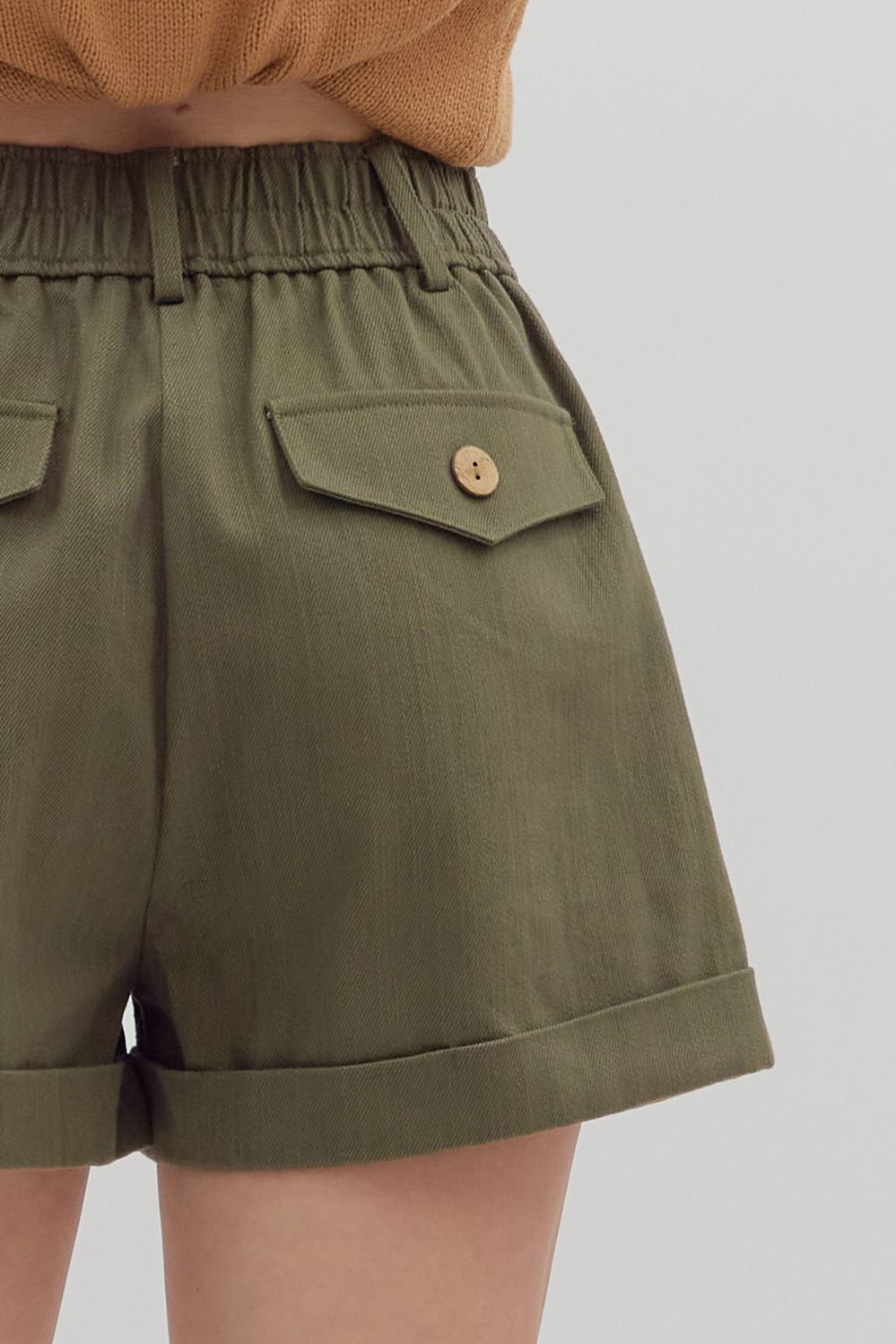 Green shorts with a button on a plain background