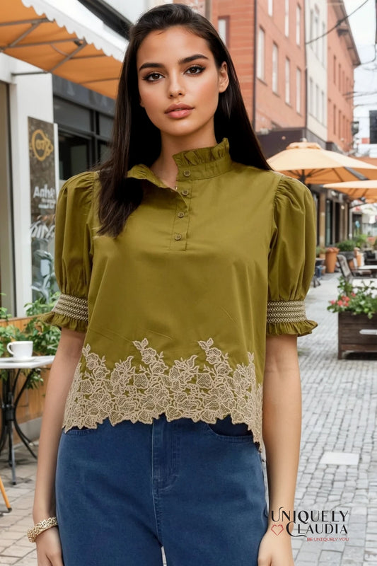 Woman wearing a green blouse with lace details on a city street.