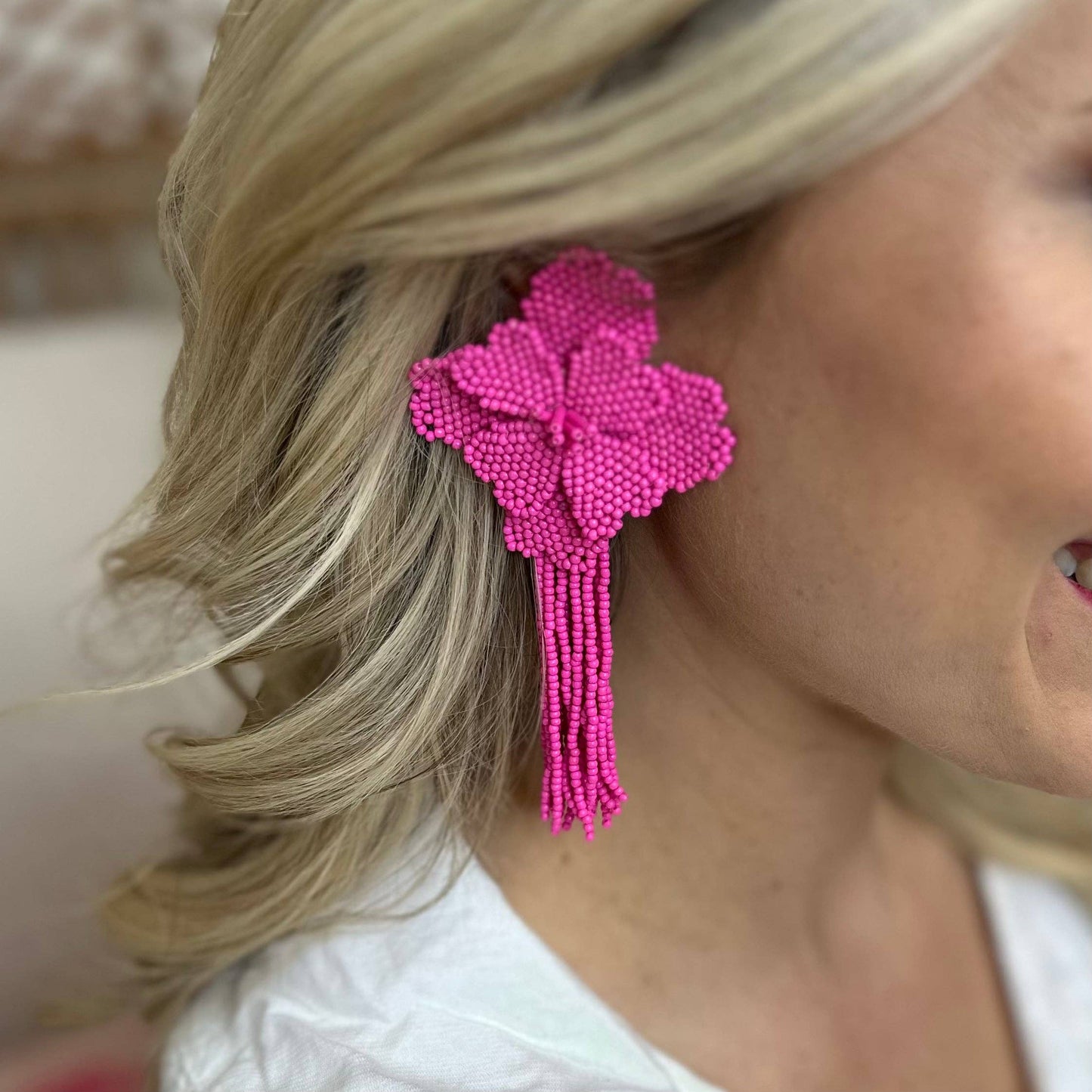 Close-up of a woman wearing pink beaded earrings with tassels.