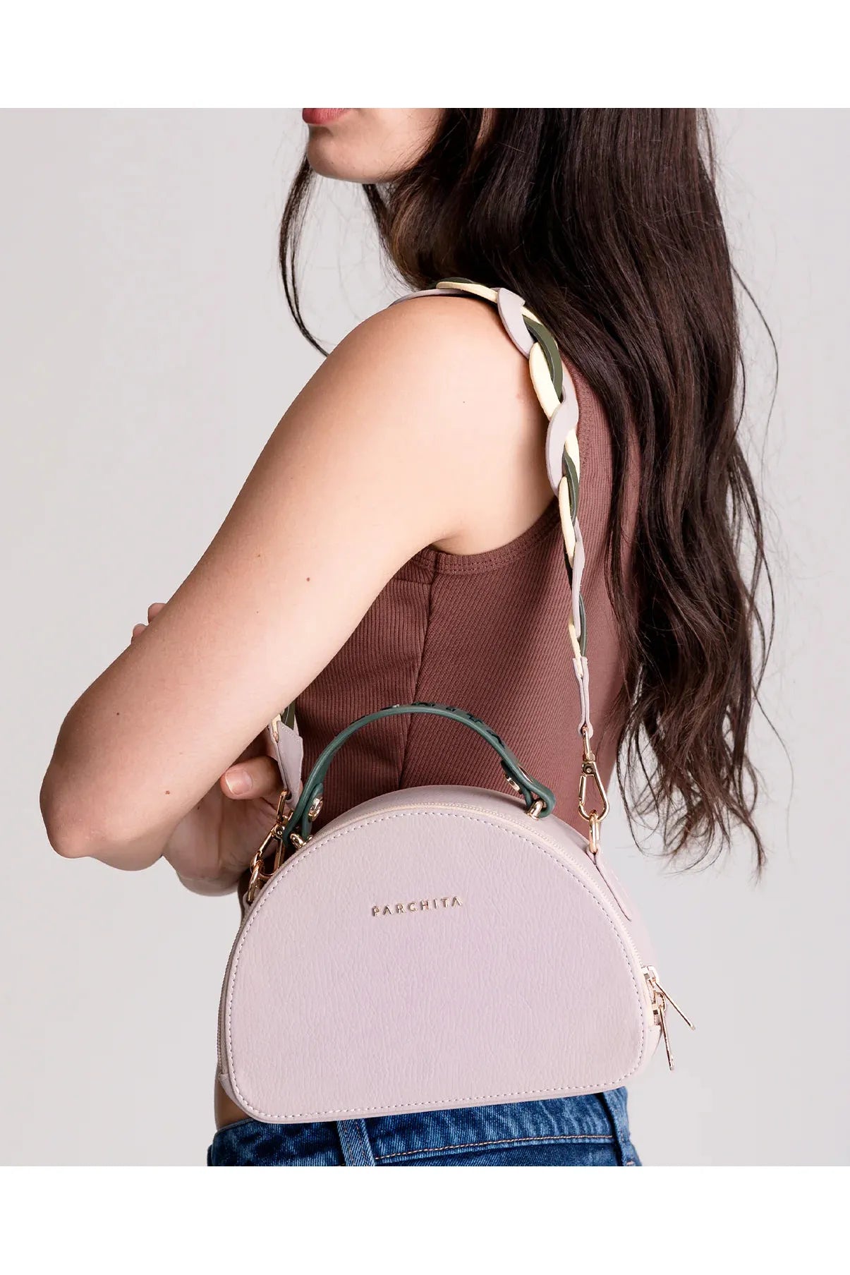 Woman holding a Parchita Brand handbag against a plain background