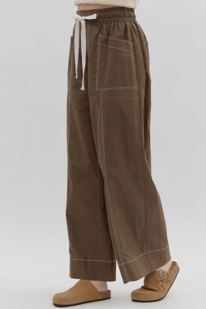 Brown wide-leg pants with a white drawstring on a light gray background