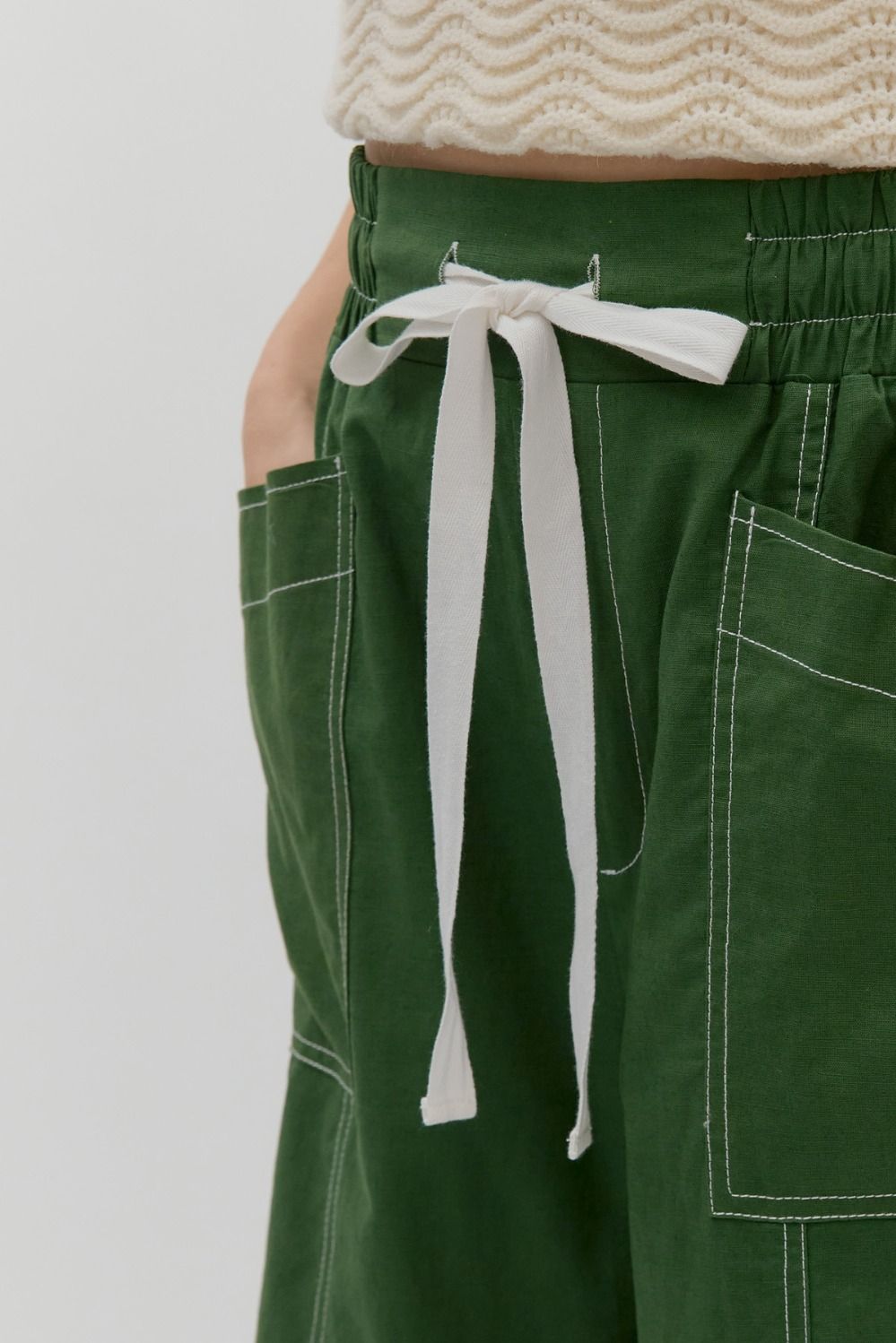 Green pants with a white drawstring on a plain background