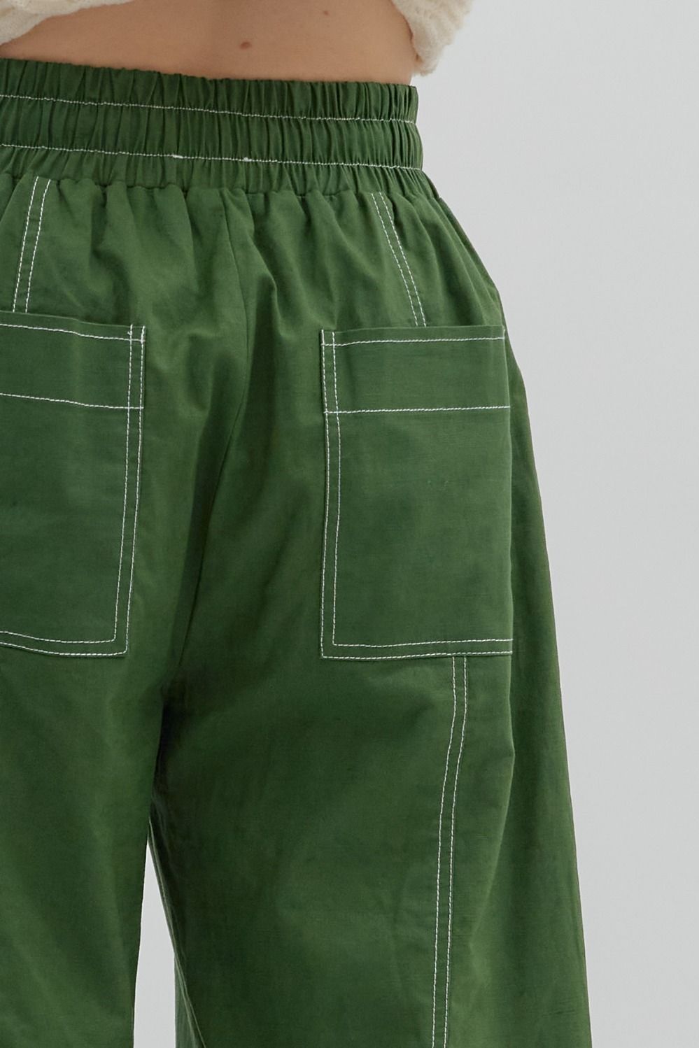 Green pants with white stitching on a plain background