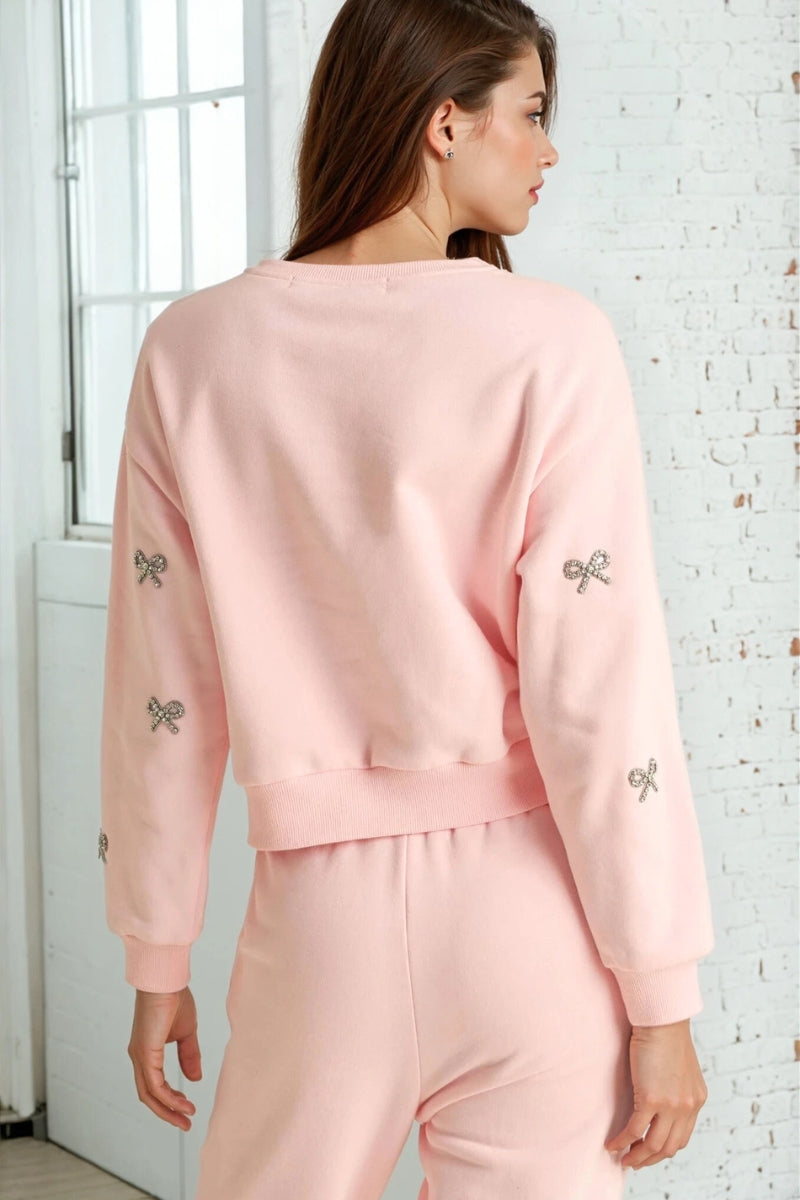 Woman wearing a pink outfit with butterfly designs in a room with white walls and a door.