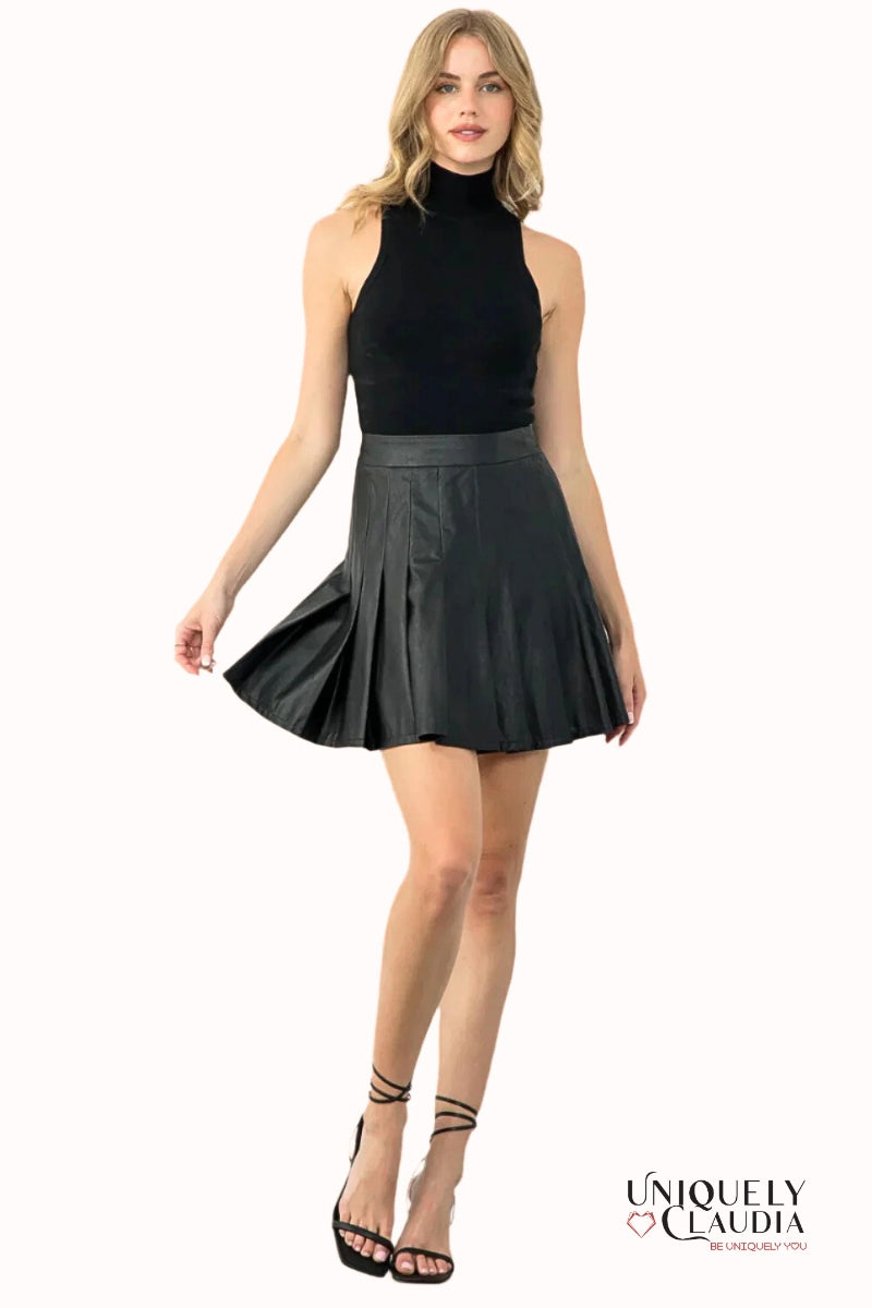 Woman wearing a black sleeveless top and black pleated skirt on a white background with 'Uniquely Claudia' branding.