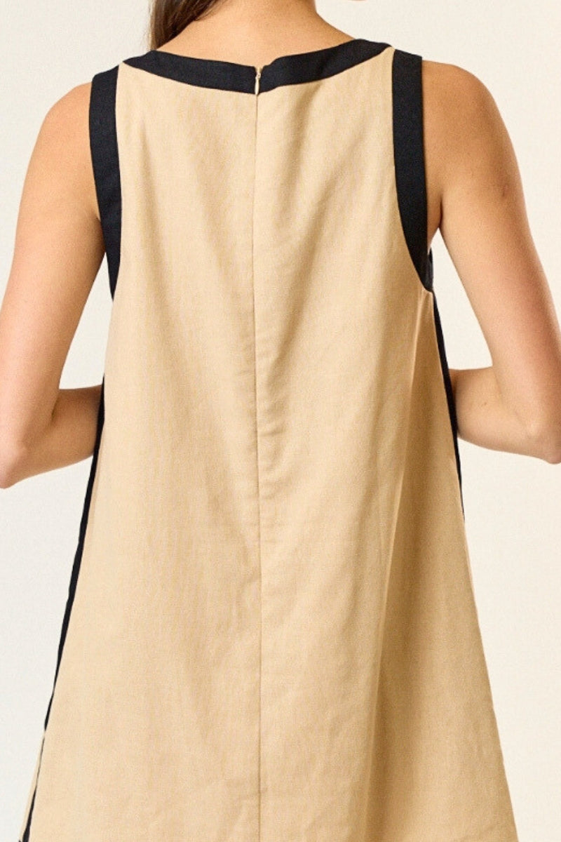 Beige dress with black trim on a plain background