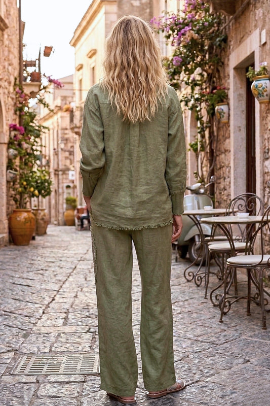 Woman in a green outfit walking down a picturesque street with flowers and tables.