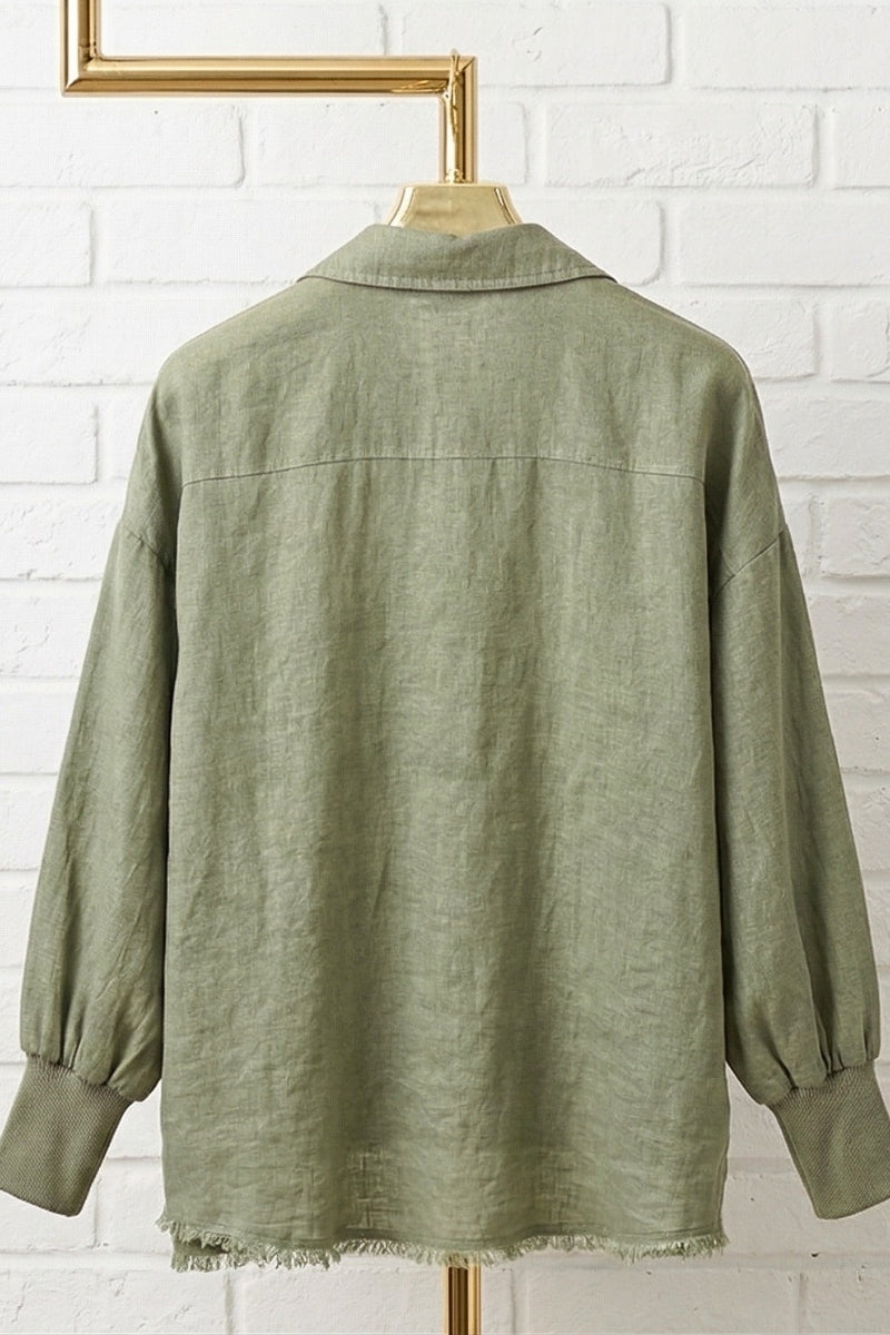 Green shirt on a hanger against a white brick wall