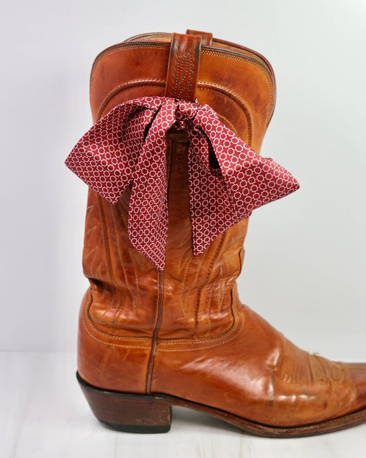 Brown cowboy boot with a red patterned bandanna on a white background