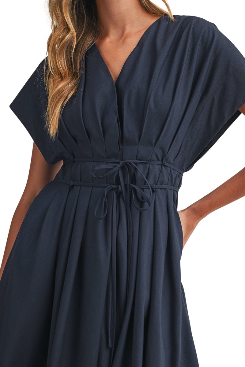 A woman wearing a navy blue wrap-style dress with short wide sleeves, a V-neckline, and a drawstring waist, shown against a plain white background.