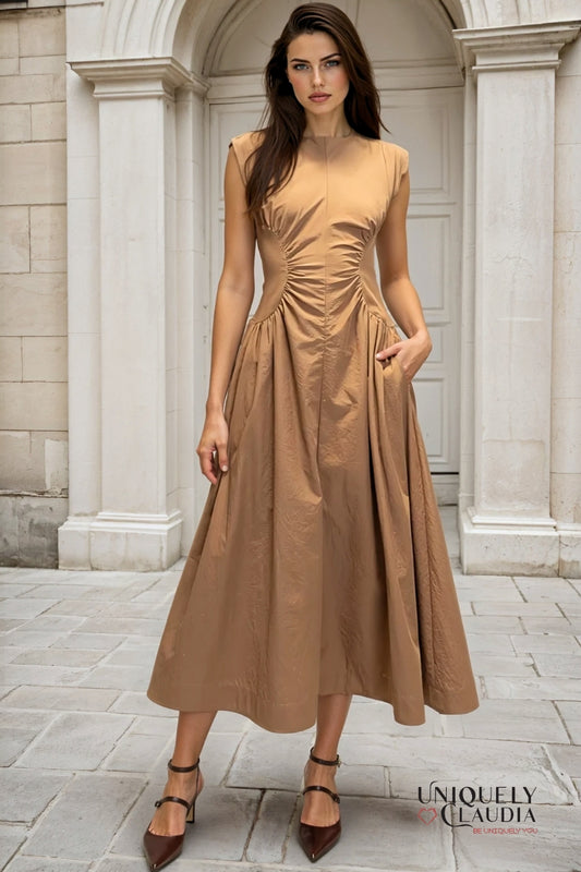 Woman wearing a brown dress standing in front of classical architecture.