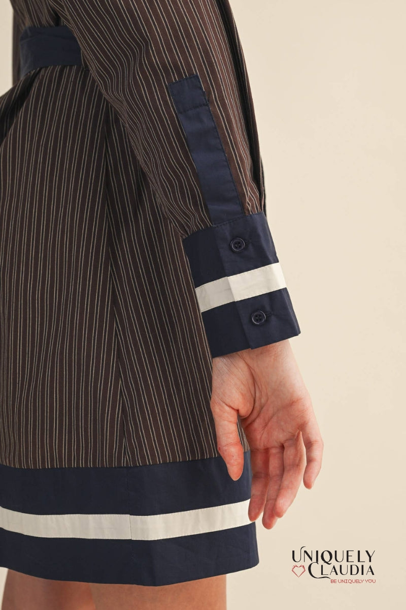Close-up of a brown pinstripe coat with navy and white accents on a beige background, featuring the brand 'Uniquely Claudia'.