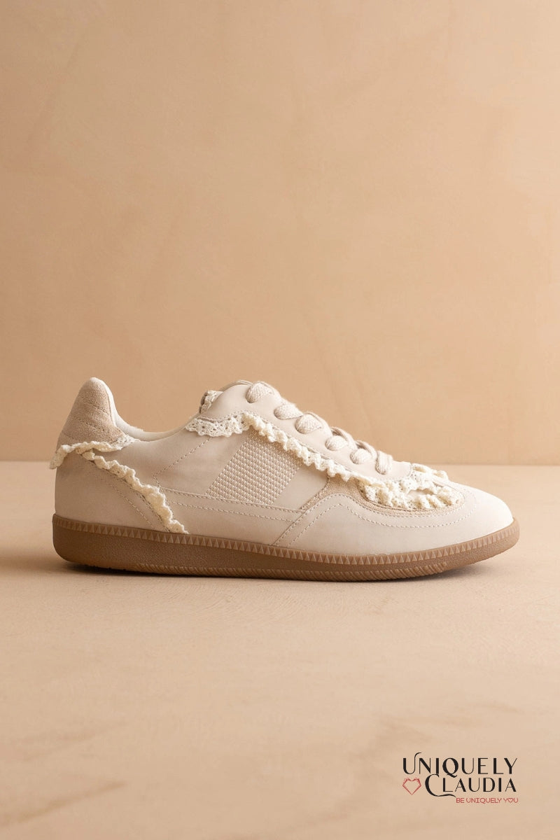 White sneaker with lace details on a beige background, featuring the brand 'Uniquely Claudia'.